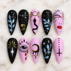 Handmade mystical press on nails in black and pastel pink featuring celestial symbols, moon, snake, evil eye, silver leaves and gothic face nail art.