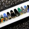 Goth press-on nails from the other end of the tray, with gold-rimmed black nails, teal scales and gold crystals