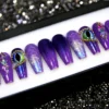 Dragon eye press-on nails from the other end of the tray: purple ombre, a green slit-pupil eye and scales