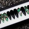 Black stiletto press-on nails from the other end of the tray, with green marble nails veined in gold leaf