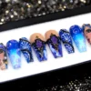 Blue ombre coffin press-on nails from the other end of the tray, showing bubble swirls, shell fans and painted faces
