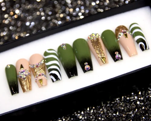 Olive-to-black fade press-on nails in a display tray, with white zebra-swirl nails and gold foil rhinestone accents