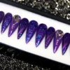 Purple stiletto press-on nails from the other end of the tray, with blue-violet glitter and crystal accent nails