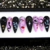 Matte black and lilac stiletto press on nails with hand-painted constellations, a snake, a dripping moon and an eye