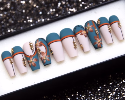 Matte coffin press-on nails from the other end of the tray: teal tips, cream nails, terracotta flowers, gold beads