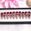 Red stiletto press on nails fully encrusted with ruby-red teardrop crystals and clear rhinestones