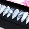 Close view of grey marble press-on nails with black ink veins, silver ridges and pearl and rhinestone clusters