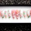 Pink and white stiletto press on nails with hand-painted cherry blossoms, green leaves, gold foil and tiny birds