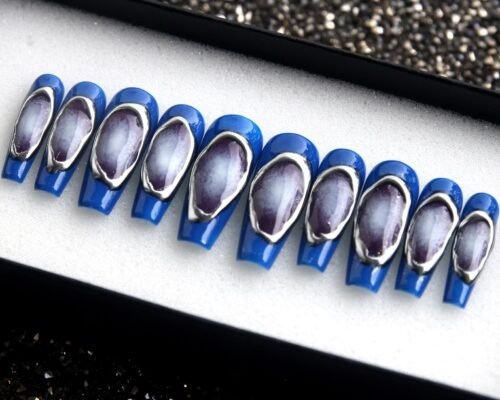 Royal blue press-on nails in a tray, each with a silver-framed window showing a purple-grey nebula