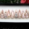 Nude glitter stiletto press on nails with rhinestone clusters, gold stars, gold chains and a crescent moon