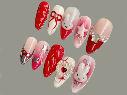 Red and blush press-on nails flat on grey, with silver chrome stars, a pearl-ringed heart, red bows and white bunny faces