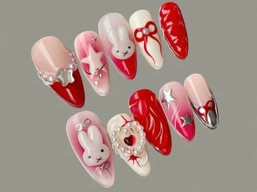 Blush to red press-on nails in a mirrored layout on grey, with pearl chains, silver stars, a ruched red nail and bunnies