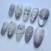 Mauve and sage press-on nails flat on blue-grey, with silver wire bows, bead swags and pearl accents