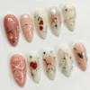 Almond press-on nails in a second layout: white lace bow outlines on peach, strawberry accents and silver wire swirls