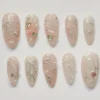 Sheer pastel pink almond press on nails with silver glitter bows, chrome hearts, pearls and marbled swirls