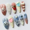 Pastel press-on nails in a mirrored layout, with a pearl-outlined star, a pink heart, cream wave texture and soft bunny faces