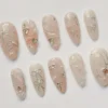 Almond press-on nails from a second angle, with marbled milky swirls, silver ribbon bows and scattered pearl dots