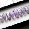 Lilac cat-eye coffin press-on nails in a black tray, with silver chrome streaks, pearly ovals and tiny flower studs