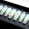 Iridescent pearl aurora coffin press-on nails in a black tray, with sculpted swirls, pink gems and a crystal heart