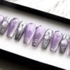 Angled view of lavender coffin press-on nails, alternating cat-eye lilac with silver chrome drip nails and small studs