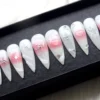 Press-on nails from the other end of the tray: white with pink blush hearts, silver wire swirls, bows and a star