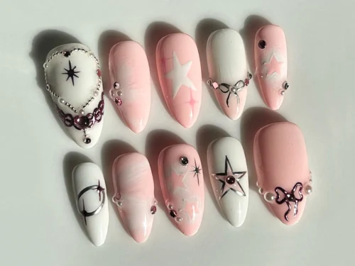 Pink and white press-on nails from the other side, with a pearl heart-outline nail, a compass star and a silver crescent
