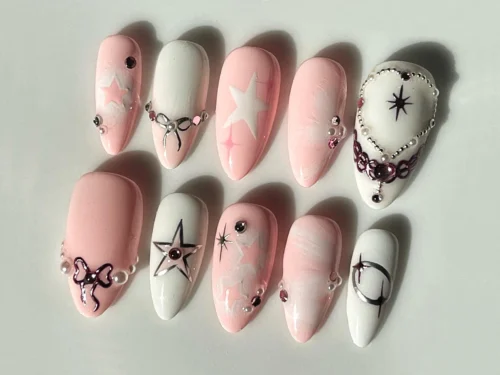 Baby pink and white Y2K almond press-on nails with white stars, tiny silver bows, rhinestones and a dark star outline