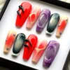 Angled view of red, purple and teal coffin press-on nails, showing black raised drips and peach ombré nails with dots