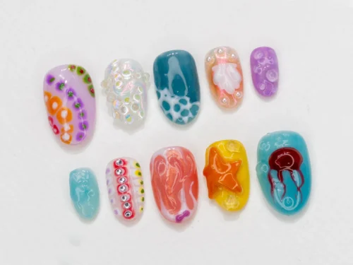 Ocean-themed oval press-on nails in a mirrored layout, with a beaded dotted nail, a seashell nail and iridescent bubble tones