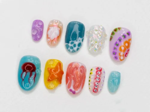 Short oval press-on nails flat on white in teal, yellow, coral and lilac, with a starfish, a jellyfish and dotted coral