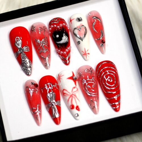 Gothic press-on nails from another angle: a red spiral nail, silver chrome bows, a white heart nail and star details