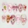 Pink press-on nails in the other order, with gingham bows, a lipstick kiss, strawberries and a cat in a heart