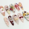 Stiletto press-on nails from a second angle, with a strawberry cream cake nail, a small bear, cherries and pink heart gems