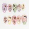 Pastel lilac, peach, sage and yellow almond press on nails with tiny cat photos, holographic bows, flowers and silver chains