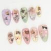 Kitty press-on nails from another angle, with peach and sage tips, a black-and-white cat on the largest nail and small bows