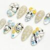 Pastel checkerboard press-on nails from another angle, with painted white puppies, blue and yellow bows and blue dots