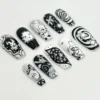 Coffin press-on nails in black and white from a rotated angle, with a bold spiral nail, drawn faces and star dots