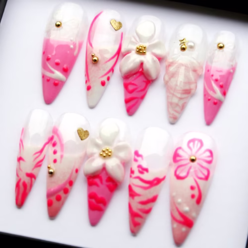 Hot pink and white press-on nails on a tray in a different order, with 3D daisies, gold heart studs and swirl lines