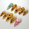 Pizza slice press-on nails from another angle, with a mint green nail of handwritten order notes and a checkered lid