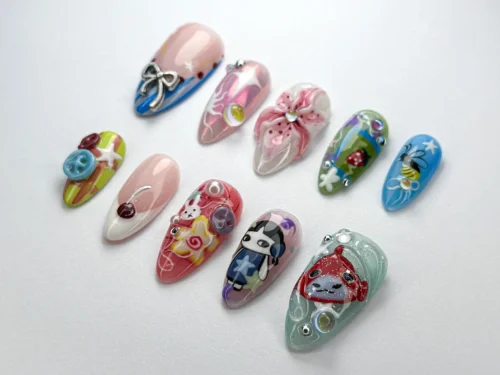 Kawaii press-on nails from another angle, with a bunny nail, a red ladybug, a silver bow and teal cartoon-face nails