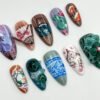 Hand-painted press-on nails on white: a purple cat nail, a folding fan, a teapot, blue porcelain pattern and a green figure