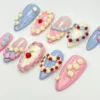 Cake-style press-on nails from another angle, with a cherry on a cream heart nail and blue and pink piped borders