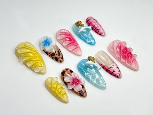 Almond press-on nails laid flat with raised yellow and pink petal ridges, leopard print, tiger stripes and a 3D dolphin