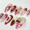 Strawberry gingham press-on nails from another angle, with a purple check nail, a red polka-dot nail and a 3D cherry cluster