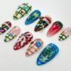 Plaid and bee press-on nails from another angle, with a white piped bow on red, pink gingham and colourful gem stars