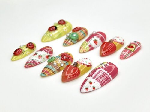 Top view of strawberry press-on nails in a long almond shape, with red heart berries, a green button and tiny berry prints