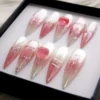 Angled view of rosy ombré press-on nails, showing thin silver chrome tracery and a glossy pink heart accent