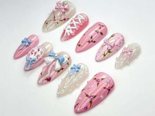 Coquette press-on nails from another angle, with a floral bouquet nail, white and blue bows and pearl-dotted sheer tips