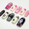 Coffin press-on nails from another angle, with a black and red striped nail, a pink striped tip, grey 3D stars and a pink gem