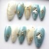 Press-on nails laid flat with shell ridges, a gold wire bow, starbursts and a pearl and crystal accent nail